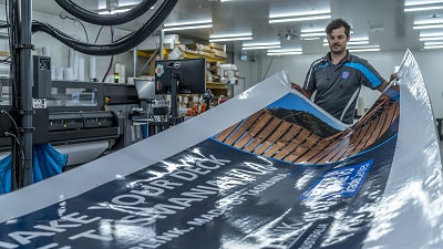 Think Big Printing employee in factory holds large printed sign.